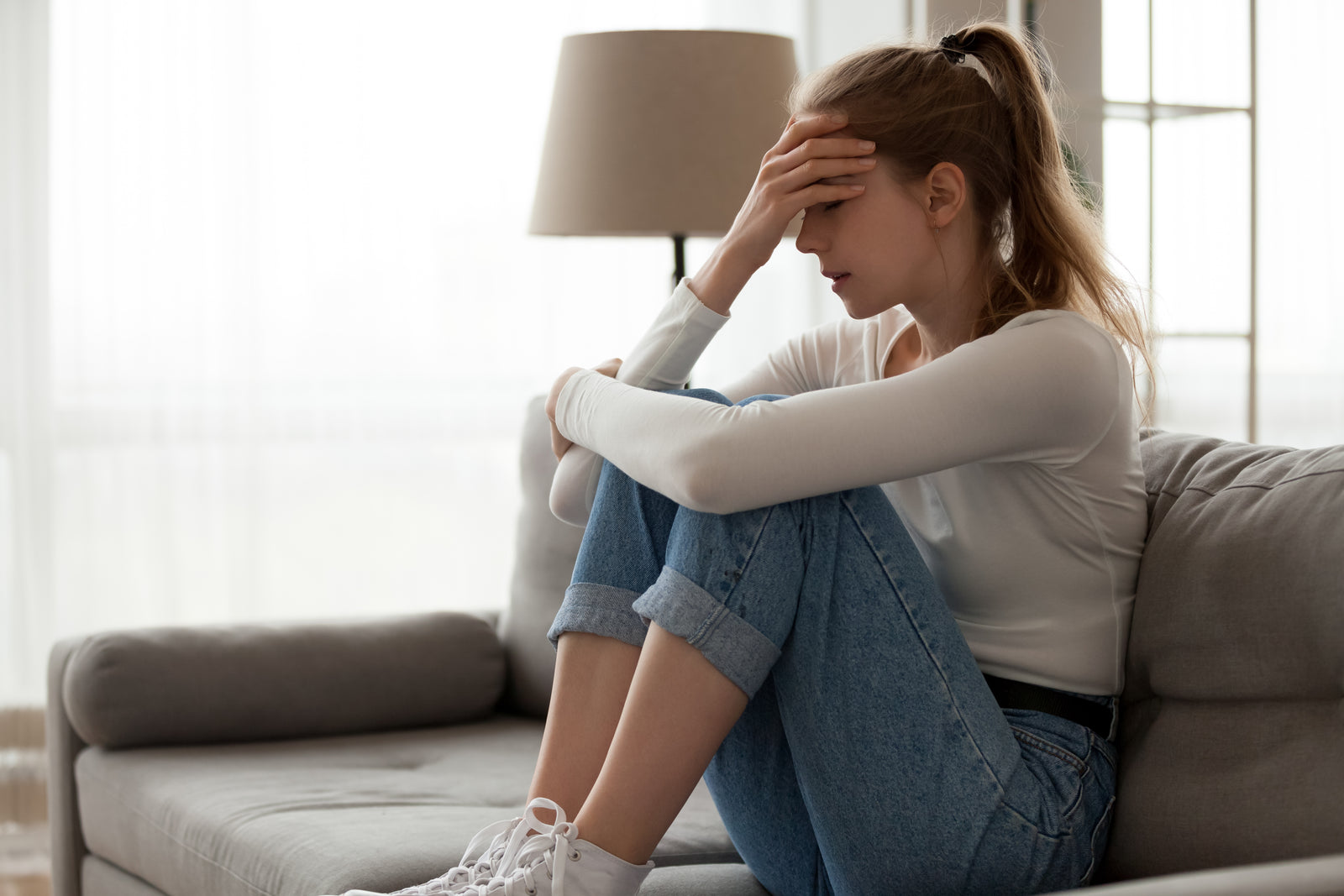 Girl in a sofa, covering her face