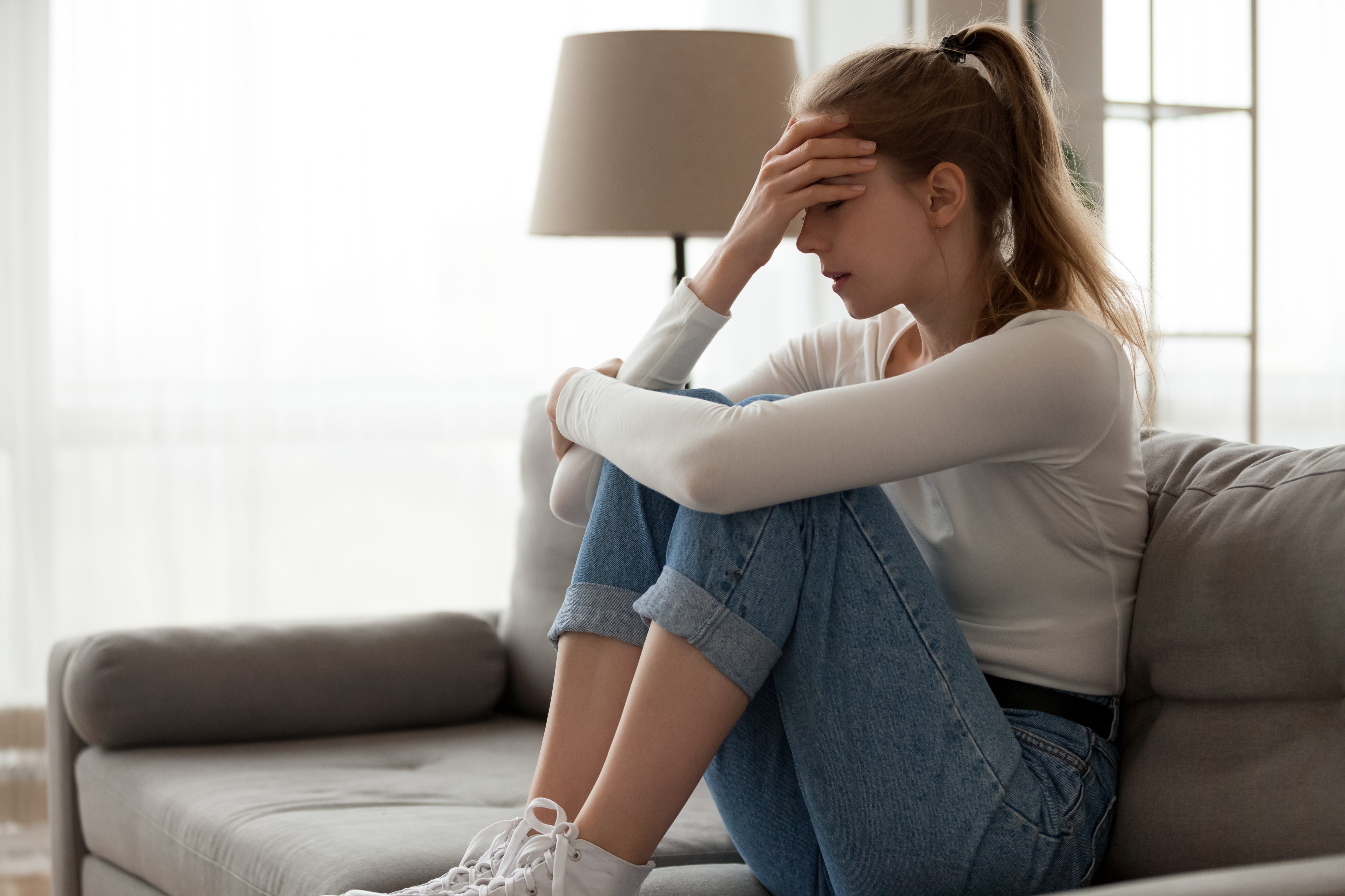 Girl in a sofa, covering her face