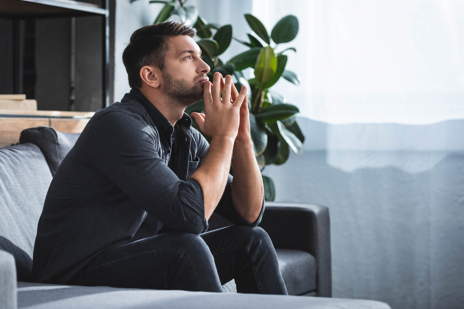 Stressed man looking at the sky sitting in a couch