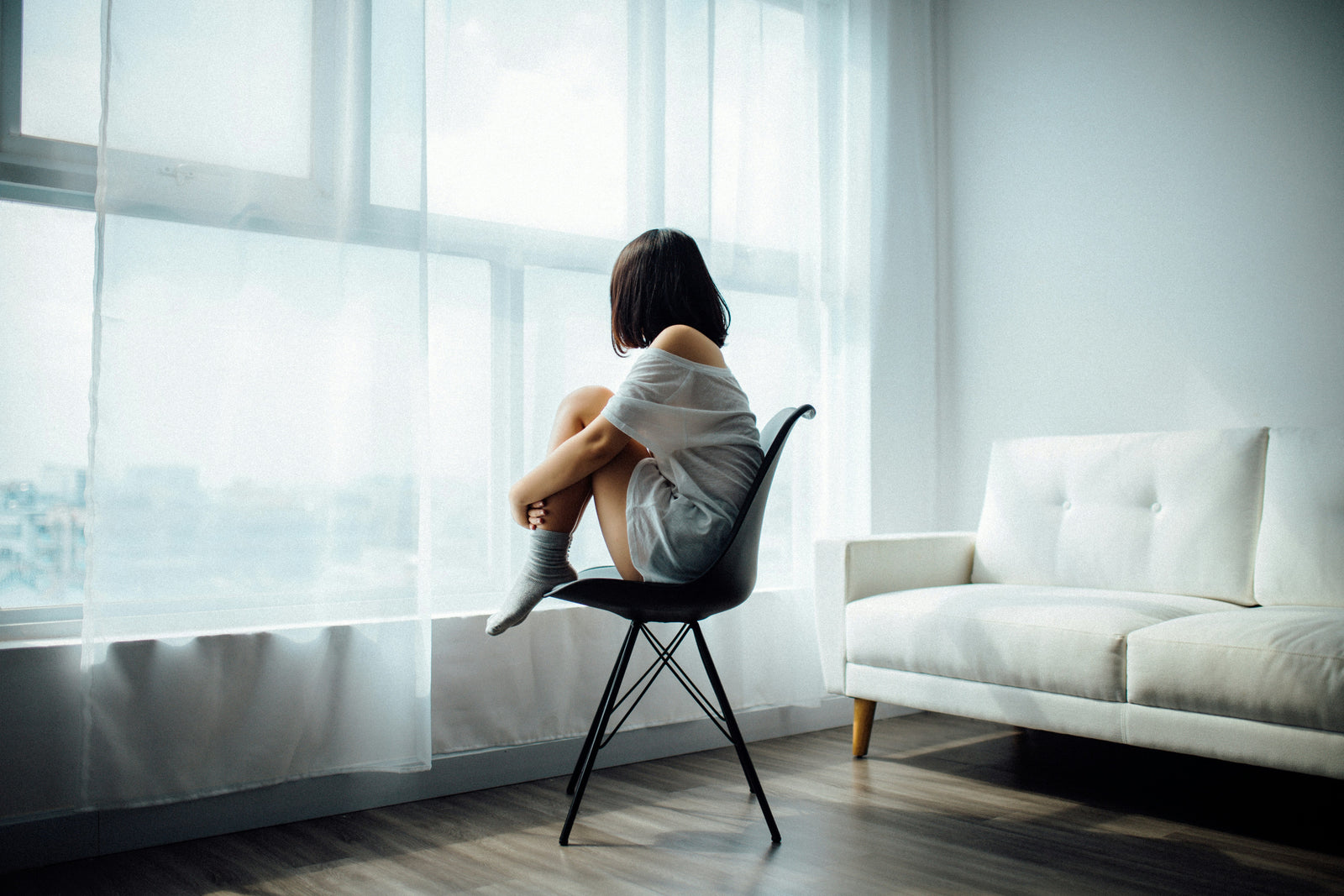 woman sitting on a chair looking through the window